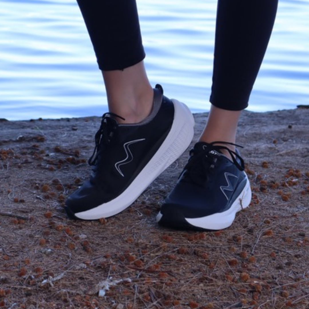 MBT-1000 womens black sneakers with white soles on rocky surface with water in background